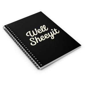K&ouml;nnte beinhalten: Schwarzes Spiralnotizbuch mit dem Text "Well Sheeyit" in cremefarbener, kursiver Schrift. Das Notizbuch ist abgewinkelt und zeigt die Spiralbindung und den oberen Einband mit dem Text. Der Hintergrund ist wei&szlig;.