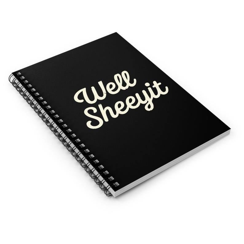 K&ouml;nnte beinhalten: Schwarzes Spiralnotizbuch mit dem Text "Well Sheeyit" in cremefarbener, kursiver Schrift. Das Notizbuch ist abgewinkelt und zeigt die Spiralbindung und den oberen Einband mit dem Text. Der Hintergrund ist wei&szlig;.