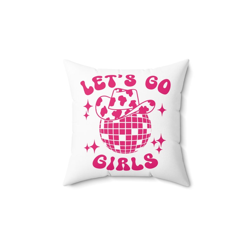May include: White pillow with pink text that reads "Let's Go Girls" with a pink disco ball and a pink cowboy hat with white spots on top of the disco ball.