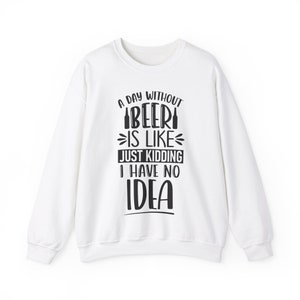 May include: White sweatshirt with a black graphic print that reads "A day without beer is like... just kidding I have no idea".