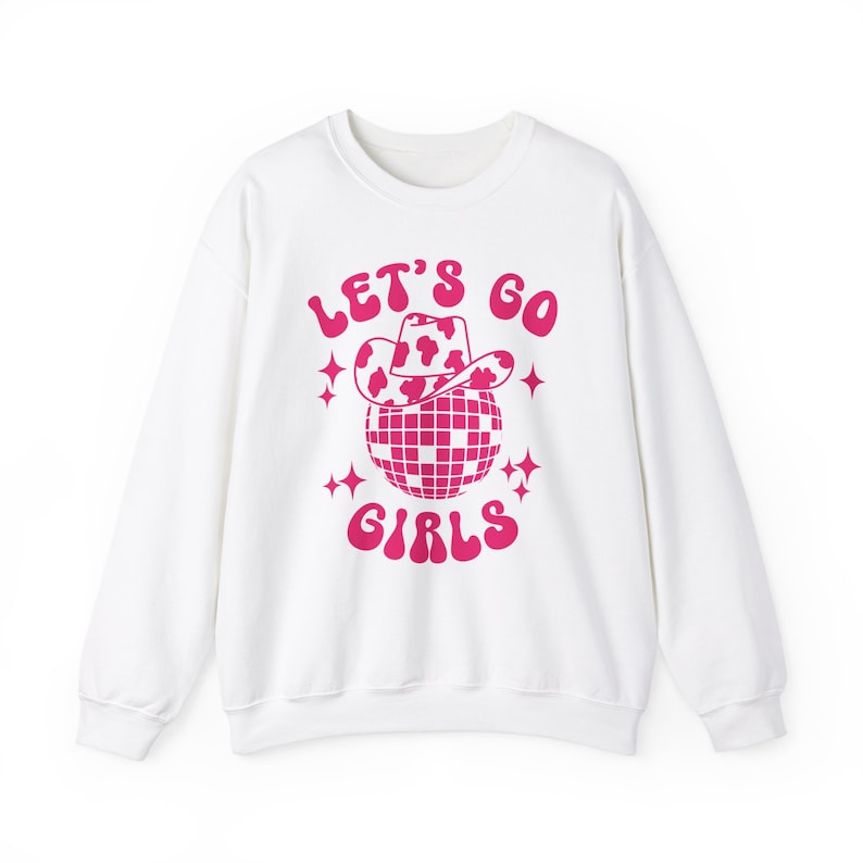 May include: White sweatshirt with a pink graphic of a disco ball wearing a cow print cowboy hat. The text "Let's Go Girls" is written in pink.