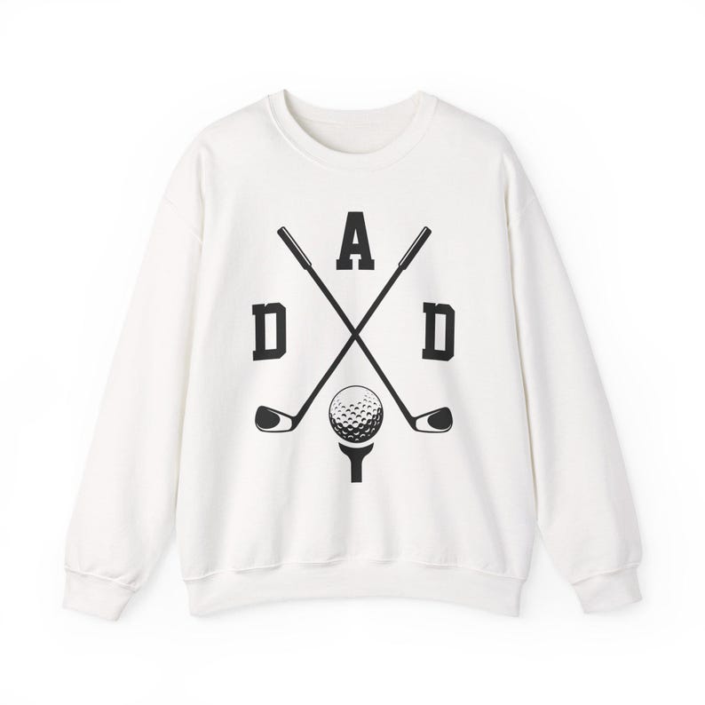 May include: White sweatshirt with a black graphic design featuring the word "DAD" with crossed golf clubs and a golf ball on a tee. The design is centered on the front of the long-sleeved crew neck sweatshirt.