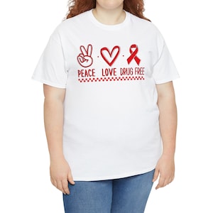 May include: White t-shirt with a red peace sign, heart, and ribbon with the text "Peace Love Drug Free".