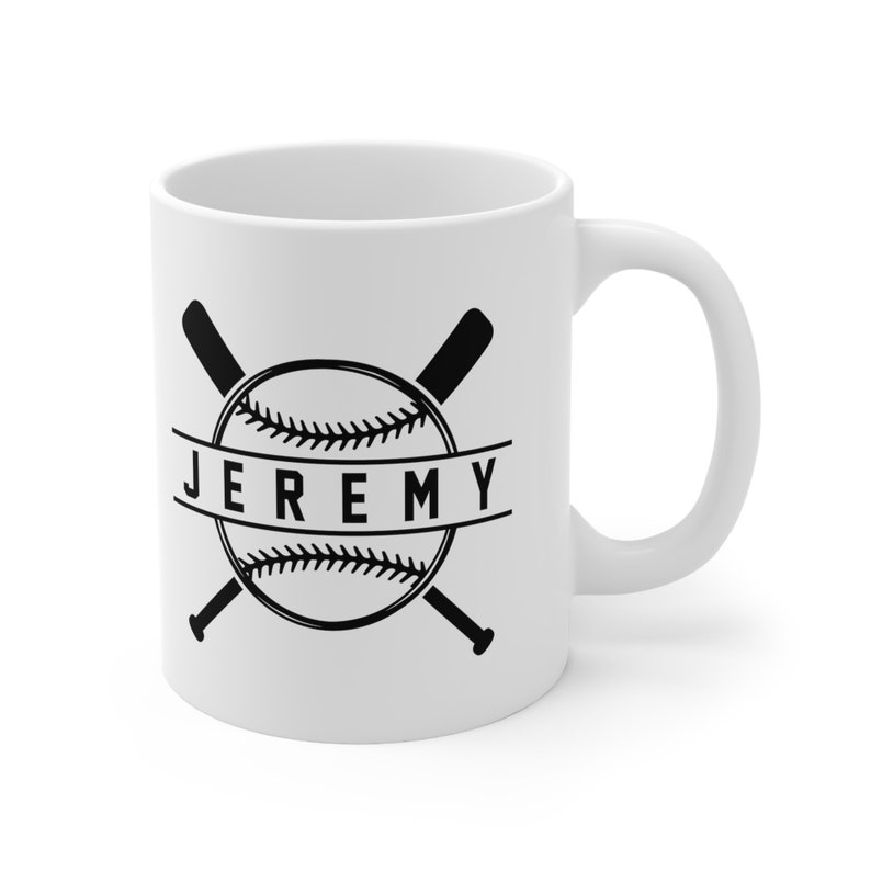 K&ouml;nnte beinhalten: Wei&szlig;e Keramiktasse mit einem schwarzen Baseball- und gekreuzten Fledermausdesign. Der Text "JEREMY" ist auf einem Banner um den Baseball gedruckt.