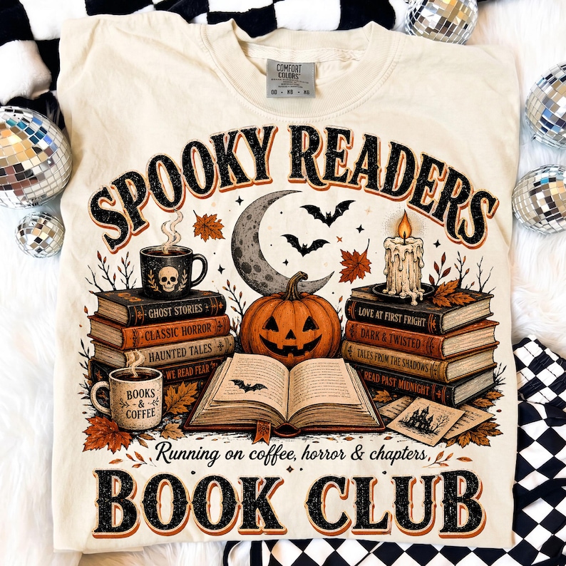 May include: A cream-colored t-shirt featuring a graphic print with the text "SPOOKY READERS" and "RUNNING ON COFFEE, HORROR & CHAPTERS, BOOK CLUB". The design includes stacks of books, a jack-o'-lantern, a crescent moon, bats, and a candle.