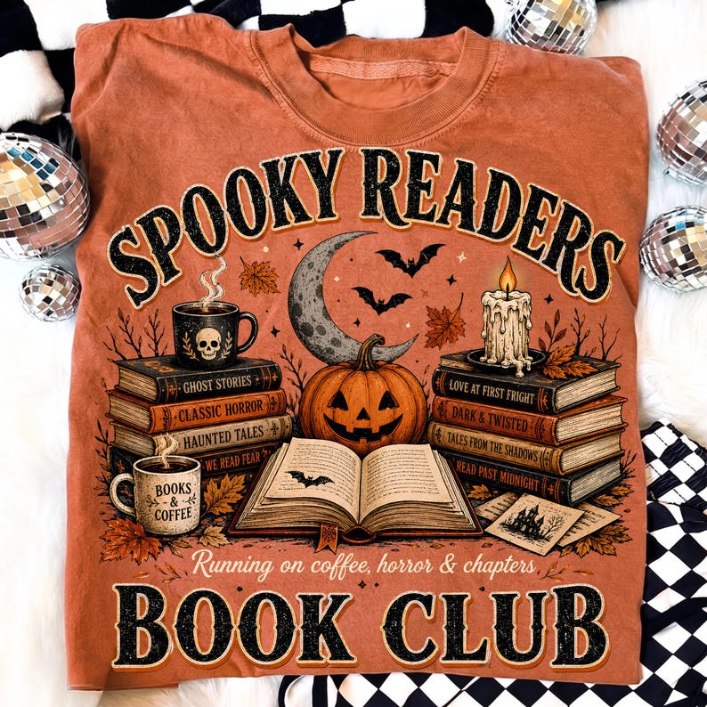 May include: A rust-colored t-shirt featuring a graphic with the text "SPOOKY READERS BOOK CLUB" and "Running on coffee, horror & chapters". The design includes stacks of books, a jack-o'-lantern, a crescent moon, bats, and a lit candle.