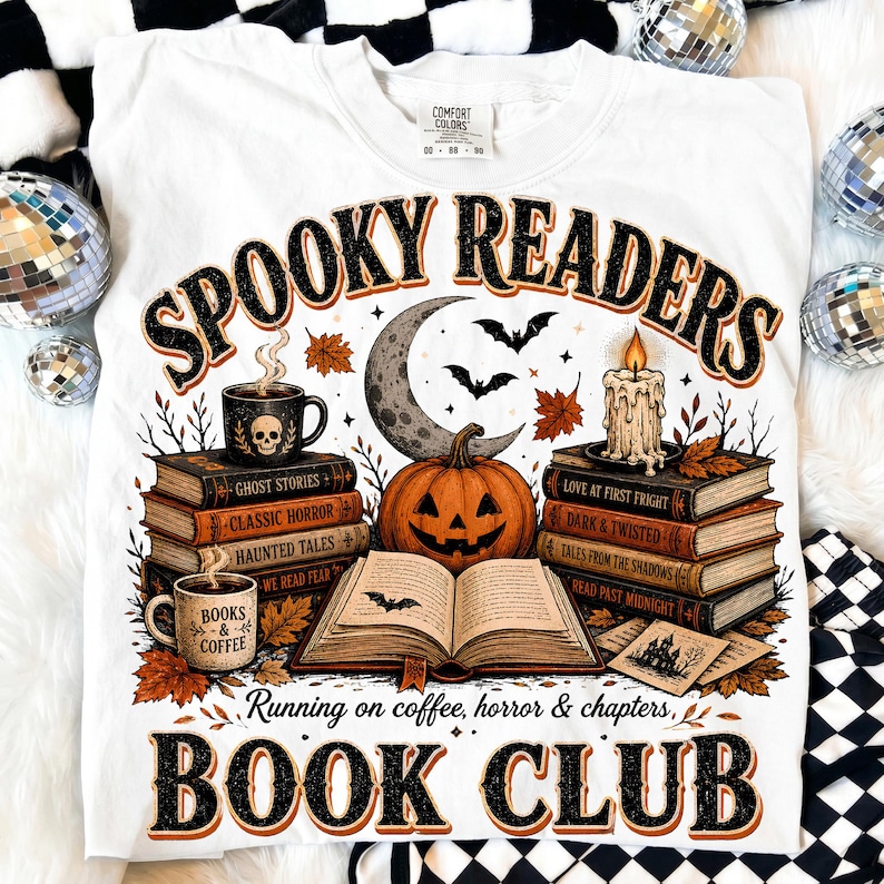May include: A white t-shirt featuring a graphic print with the text "SPOOKY READERS" and "BOOK CLUB". The design includes stacks of books, a jack-o'-lantern, a crescent moon, bats, a lit candle, and two mugs with the text "BOOKS & COFFEE".
