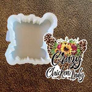 May include: A clear, flexible silicone mold in a unique shape, next to a sticker with a leopard print chicken design and the words "Crazy Chicken Lady" in black script.