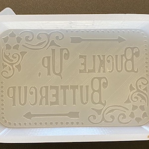 May include: White plastic tray with a decorative design and the text "Buttercup Buckle Up" in a vintage style font.
