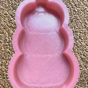 Può includere: Stampo in silicone rosa a forma di torta a tre piani. Lo stampo ha una finitura liscia e lucida.