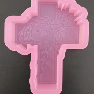 May include: Pink silicone mould of a cross with a detailed image of Jesus Christ wearing a crown of thorns.