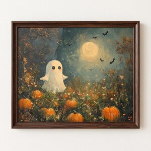 May include: A framed wall art print depicting a white ghost with large black eyes and pink cheeks standing in a field of orange pumpkins. The scene features a dark forest background, a bright full moon, and several black bats flying in the night sky.