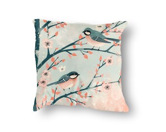May include: A decorative throw pillow with a blue and pink floral pattern featuring two birds perched on branches. The background is a light blue with a subtle watercolor effect.