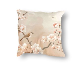 May include: A decorative throw pillow with a beige background featuring a delicate floral design of white and pink blossoms and a small brown bird perched on a branch.
