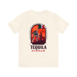 May include: A white t-shirt with a graphic print of a robot holding a Mexican flag in a desert landscape. The text "Tequila Gundam" is printed below the graphic. The text "Black Enuff Neo Mexico Chico Rodriguez Black Enuff" is printed in a circle around the graphic. The text "Estd 1992" is printed below the circle.