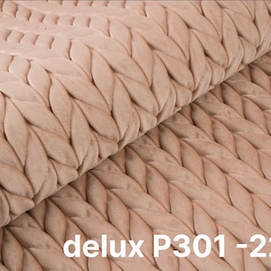 Op de afbeelding: Close-up van een beige stof met een geweven patroon. De stof heeft een zacht, getextureerd oppervlak. De tekst "delux P301-2244" is op de stof gedrukt.