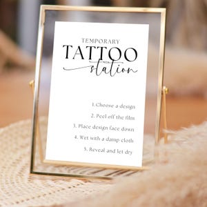 May include: A white sign with black text that reads "Temporary Tattoo Station". The sign lists instructions for applying temporary tattoos: 1. Choose a design, 2. Peel off the film, 3. Place design face down, 4. Wet with a damp cloth, 5. Reveal and let dry.