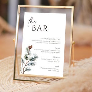 Puede incluir: Un cartel de bar de boda imprimible con un diseño de rama de pino acuarela. El cartel enumera los cócteles de autor, el vino, las bebidas espirituosas y la cerveza que se ofrecen para la recepción de la boda. El texto dice "the BAR", "Signature Cocktail", "Bride's Choice: Limoncello Prosecco", "Groom's Choice: Old Fashioned", "Wine", "Cabernet Sauvignon, Chardonnay, Merlot, Sauvignon Blanc", "Spirits", "Vodka, Whiskey, Rum, Gin, Tequila Brandy", "Beer", "IPA, Pilsner, Stout, Wheat Beer, Amber Ale".