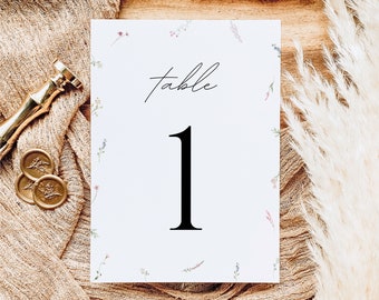 May include: White card with a floral border and the text "table 1" in black.