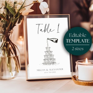 May include: A printable table number sign featuring a champagne tower illustration and the text "Table 1". The sign also includes the names "Megan & Alexander" and the date "July 7th 2024".