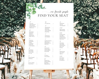 May include: A white wedding seating chart with green foliage and the text "our favorite people FIND YOUR SEAT". The chart lists names in alphabetical order with table numbers.