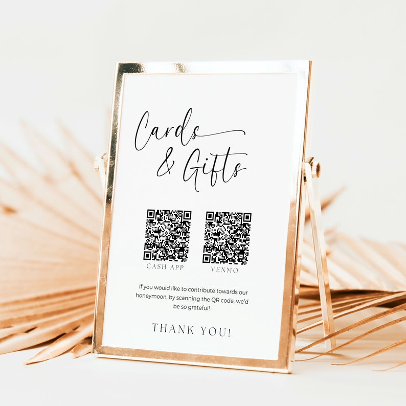 K&ouml;nnte beinhalten: Ein wei&szlig;es Schild mit goldener Umrandung, auf dem der Text "Cards & Gifts" in schwarzer Kursivschrift steht. Darunter sind zwei schwarz-wei&szlig;e QR-Codes abgebildet, die mit "Cash App" und "Venmo" beschriftet sind. Auf dem Schild steht: "Wenn Sie zu unseren Flitterwochen beitragen m&ouml;chten, scannen Sie den QR-Code. Wir w&auml;ren Ihnen sehr dankbar! Vielen Dank!"