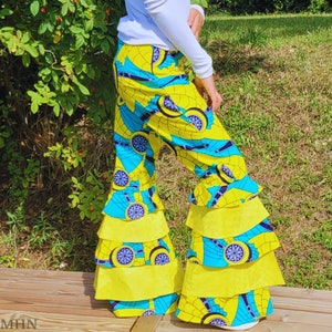 May include: Yellow and blue patterned trousers with multiple layers of frills. The trousers have a wide leg style and are made of a lightweight fabric.