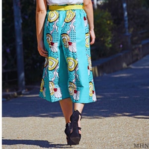 May include: A woman wearing a pair of blue and white patterned culottes with a yellow waistband. She is wearing black high heels.