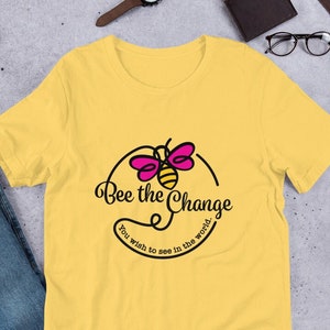 May include: Yellow short-sleeved t-shirt with a bee graphic and the text "Bee the Change you wish to see in the world."