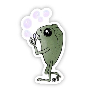 May include: A green frog with big eyes blows bubbles with a wand. The frog is standing on one leg and has a whimsical expression.