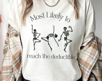 May include: White t-shirt with a graphic of three skeletons dancing and the text "Most Likely to reach the deductible".