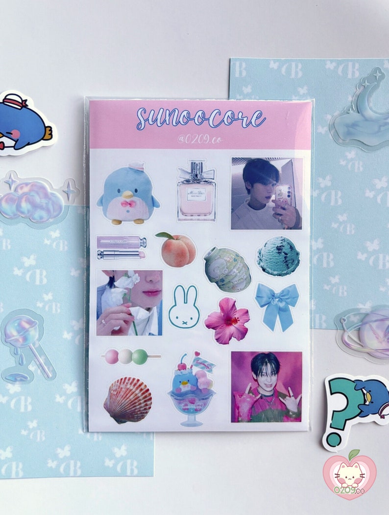 May include: A sheet of stickers with a variety of designs, including a penguin, perfume bottle, peach, ice cream, and a photo of a person. The stickers are in various colors, including pink, blue, and white. The text "SUNOOCORE" is written on the sheet.