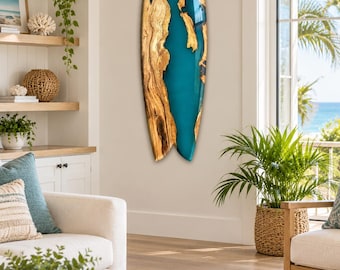 Op de afbeelding: Een surfboardvormig wandkunstwerk met een natuurlijke houtnerfafwerking aan de buitenranden en een gladde, glanzende, levendige turquoise harsrivier die door het midden stroomt, wat een opvallend contrast vormt tussen het organische hout en de hars.