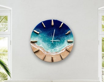 May include: A round wall clock with a beach scene. The clock face is a blue ocean with white waves crashing on a sandy beach. The clock hands are silver.