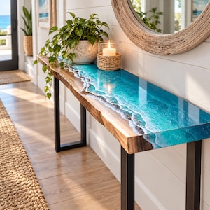 May include: A rectangular console table featuring a natural live-edge wood slab top with a glossy blue and turquoise resin inlay that mimics ocean waves. The table is supported by two black metal legs and holds a potted plant and a candle.