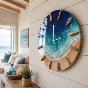 May include: A circular wall clock featuring a glossy resin finish that mimics an ocean shoreline. The design transitions from deep blue at the top to turquoise waves and a sandy beige base. Twelve pieces of driftwood serve as hour markers.