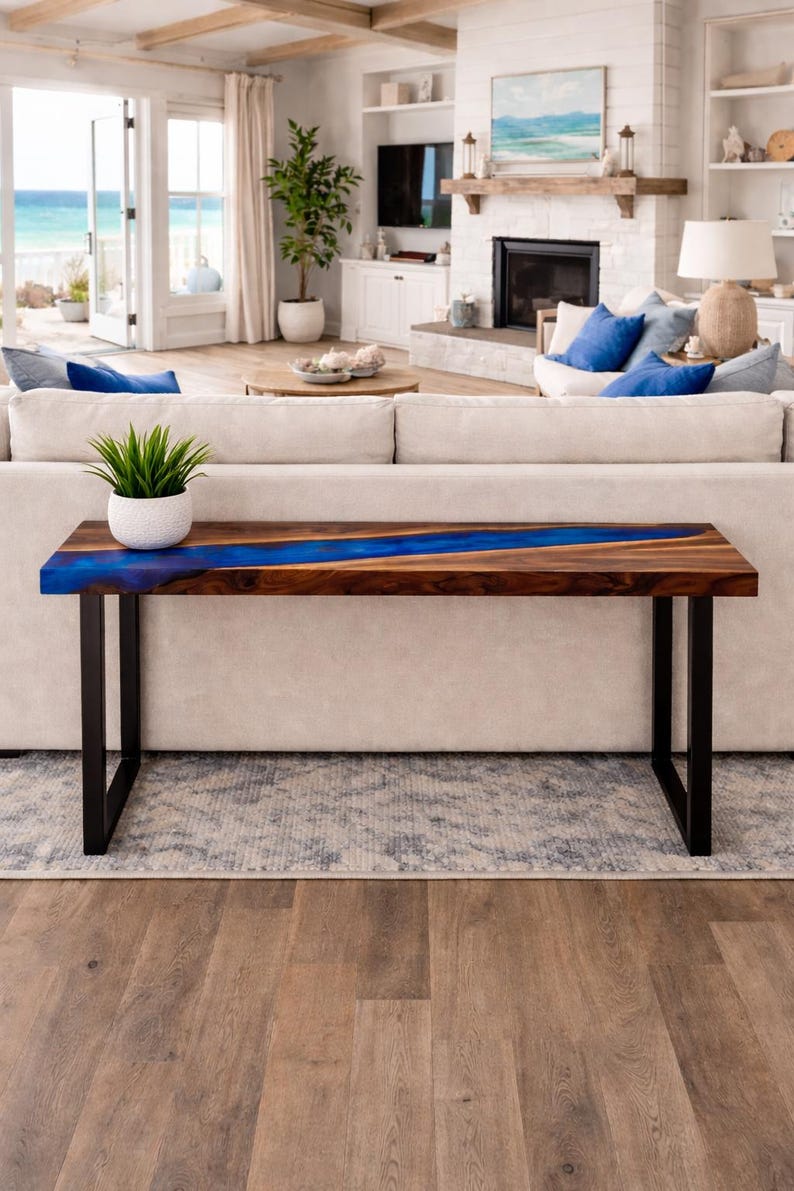 May include: A modern wooden console table with a dark walnut finish and a vibrant blue resin river. The table has black metal legs and a rectangular shape. A small potted plant sits on the table.