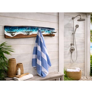 May include: A wooden wall-mounted coat rack with four metal hooks, featuring a blue and white resin wave design. A blue and white striped towel hangs from the hooks. The scene is set in an outdoor shower area.