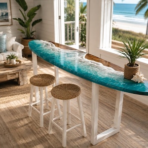 May include: A surfboard-shaped bar table with a turquoise and white resin design, resembling ocean waves. It has a wooden top and white legs, paired with two woven-seat stools. A potted plant and seashell add coastal decor.