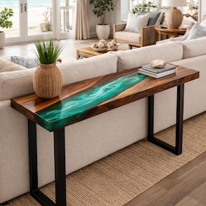 May include: A wooden console table with a vibrant teal epoxy resin river design. The table has a dark wood finish, black metal legs, and a woven basket with greenery. Books and a decorative shell sit on top.