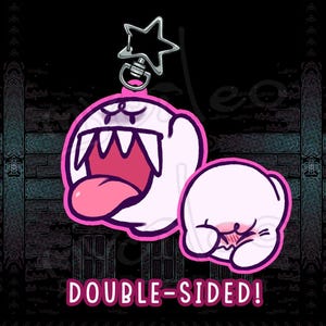 May include: Double-sided keychain featuring two cartoon ghosts with pink accents. One ghost has an open mouth with a pink tongue, and the other is blushing. The keychain has a star-shaped clasp and the text "DOUBLE-SIDED!"