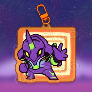 May include: A purple and green cartoon character with a large head and a menacing expression. The character is in a square frame with an orange border and a swirling pattern inside. The character is a keychain.
