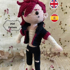 May include: Crochet pattern for a doll with red hair, black jacket, black pants, and red shoes. The pattern is available in English and Spanish.