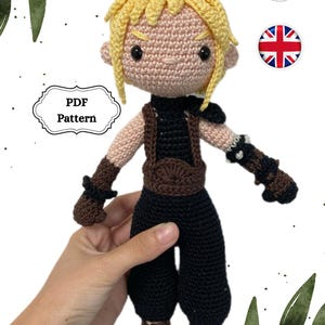 Puede incluir: Patrón de crochet para un personaje con pelo rubio de punta, que lleva un atuendo negro con detalles marrones. El patrón está disponible en formato PDF.