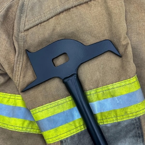 May include: A matte black metal fire tool featuring a flat, wide head with a pointed tip, a rectangular cutout, and a curved top edge. The tool has a long, cylindrical handle and is positioned against a tan fabric background with reflective strips.