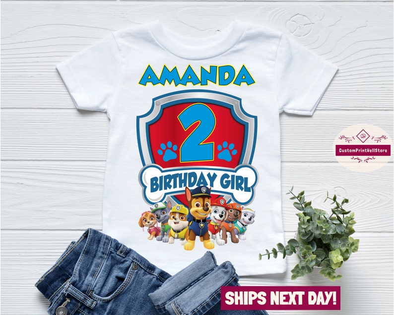 May include: White t-shirt with a red and blue Paw Patrol logo, the number 2, and the text "Amanda" and "Birthday Girl".