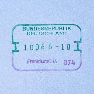 May include: A rectangular ink stamp on paper featuring the green text BUNDESREPUBLIK DEUTSCHLAND, the number 1006 6-10, and the purple text Frankfurt/OJA. 074. The stamp has rounded corners and small side indentations in a green and purple gradient.