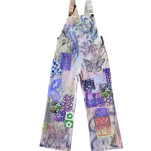 May include: Purple and green tie-dye denim overalls with butterfly and floral patches.