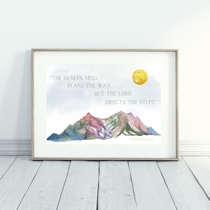 Könnte beinhalten: Ein Aquarellbild von Bergen mit einer gelben Sonne am Himmel. Das Zitat "Der menschliche Geist plant den Weg, aber der Herr lenkt die Schritte." ist in grauer Schrift mit dem Vers "Sprüche 16:9" darunter geschrieben.
