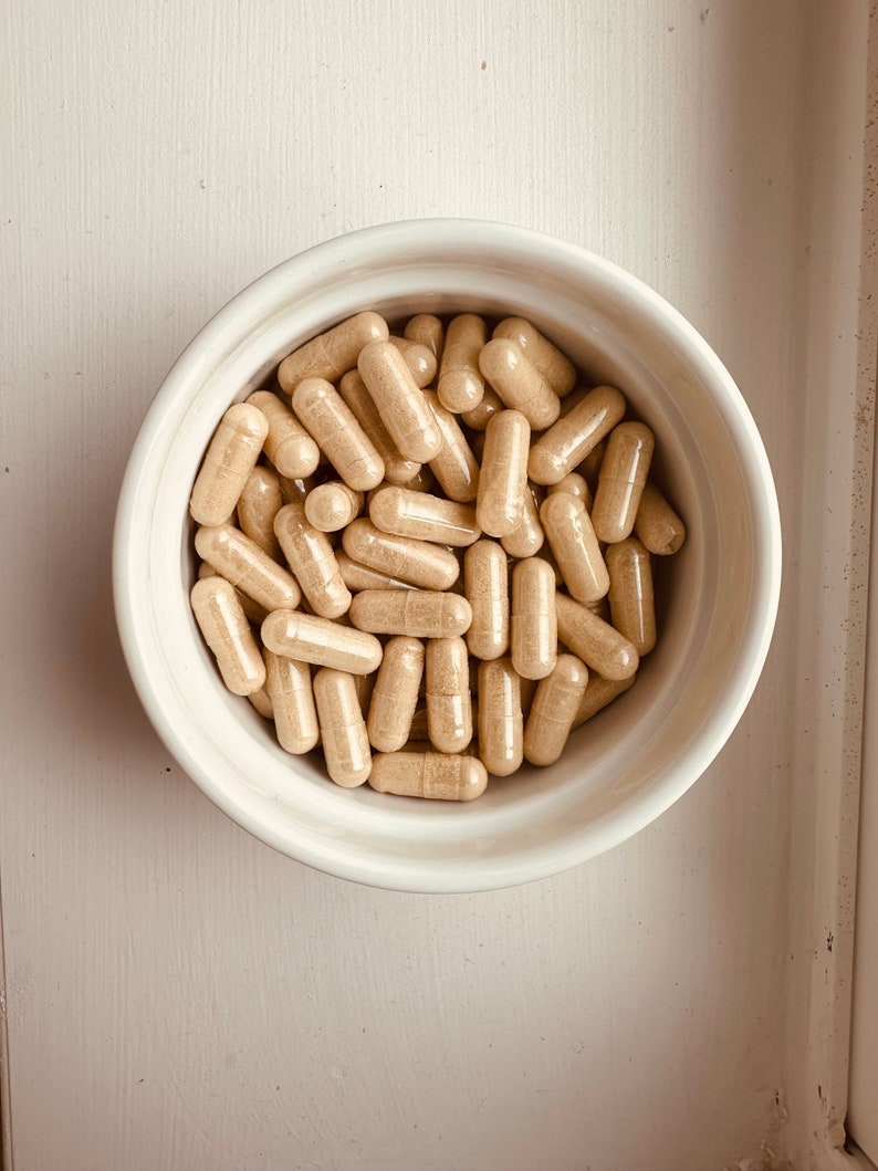 Peut inclure: Un bol en c&eacute;ramique blanche rempli d'une grande quantit&eacute; de capsules beiges.
